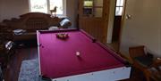 A sitting room with a brown leather suite and a snooker table.