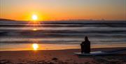 A paddleboarder enjoying the sunset from the beach