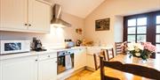 Image shows kitchen area with table and chairs and patio doors