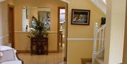 A large entrance hall area with a chair, cabinet, a staircase and a doorway leading to a bathroom.