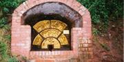 A brick fireplace in the forest filled with artfully carved logs.