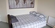 Double bed with checked bed spread and folded towels on top