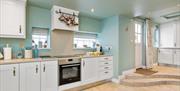 Kitchen with a hob/oven, windows and steps leading to a backdoor.