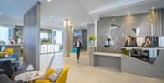 A woman walking through reception while receptionists work.