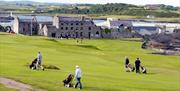 Golfers on Ardglass Golf Course in front of Club house