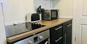 A small kitchen with a hob/oven, toaster and a microwave.