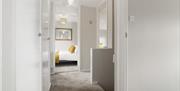 A carpeted hallway leading to a bedroom.