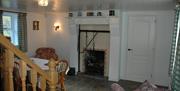 A tiled sitting area with a table, fireplace and a chair.