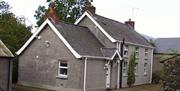 A side angle view of the front of a large grey house.