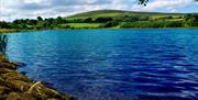 A lake with blue water and a country hill.