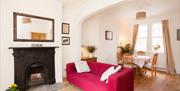 A living/dining room with a red sofa, fireplace and a table and chairs.