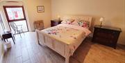 Image shows double bedroom with wood effect tiled floor and full height window onto courtyard
