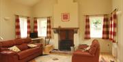 A sitting area with two red sofas, a fireplace, a small desk with a TV and windows.