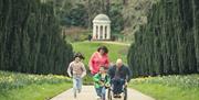 A family are walking up Yew Tree Walk at Hillsborough Castle and Gardens