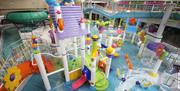 Image shows swimming pool with lots of brightly coloured slides