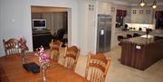 View of the open plan kitchen from the dining table and eight chairs