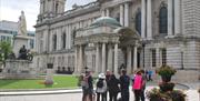 DC Tours taking a group of guests on a walking tour outside Belfast City Hall