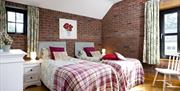 Image shows twin bedroom with beside tables and lamps, dressing table and chair