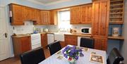 Image shows kitchen and dining area with table and chairs