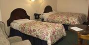 A bedroom with two single beds, a table and a chair.
