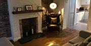 Image shows lounge area with wooden floor, sofa, chair and fireplace