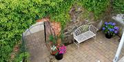 Image is of courtyard area taken from above and showing wrought iron seating, ivy on the walls and plant pots on the ground