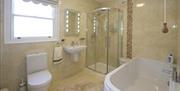 tiled bathroom with shower, bath, sink and toilet