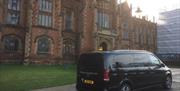 A black tour van parked outside Queens University's Lanyon building.