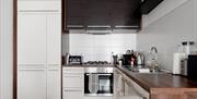 A fully kitchen with white cabinets and a dark wood bench.