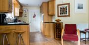 Kitchen area with a coffee maker, sink, stools and a red chair.