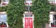 Outside image of Laurel Villa with greenery on walls and red door