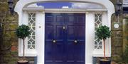Large blue double doors decorated with lamps and potted trees.