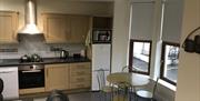 A kitchen with a small dining room table and chair set next to a window.