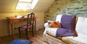 A stone room with a sofa, desk under a roof window