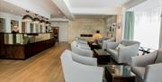 Image shows receptionist at desk in reception area. Also chairs and coffee tables