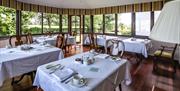 A large sun/dining room with five set tables.