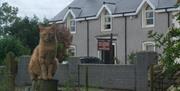 Front exterior of BnB with a sign and an orange cat.