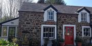 Image is of red door with glass. Property is a stone building with a small extension visible.