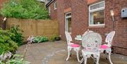 A photo of a paved back garden with flowers and garden furniture.