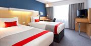 A bedroom with two single beds a desk and a TV.