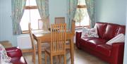 Image is of lounge with 2 red leather sofas and dining table with 4 chairs