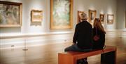 A couple sit on a bench to admire the various pieces of artwork on display at the ulster museum