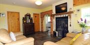 Image shows lounge area with tiled floor, 2 sofas and fireplace