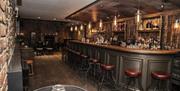 Image is of bar with low stools, tables and wooden floor