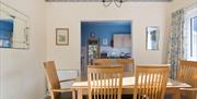 Dining room with table to seat six with a window, mirror and an entrance to the kitchen.