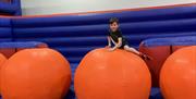 A young boy climbing on a large inflatable ball in the Inflata park.