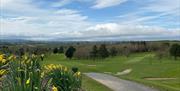 Image shows golf course, walking path and view of countryside beyond