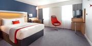 A double bedroom with a chair and a TV.