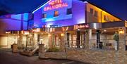 A photo of a hotel with an outdoor seating area lit up at night.