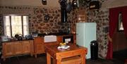 Image is of dining area with table, large fridge and feature stone walls